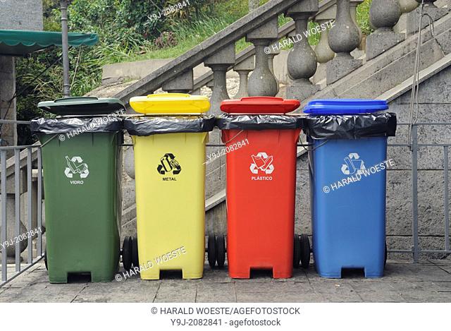 Rio de Janeiro, Brazil. Four coloured waste bins lined up: green for glass (vidro), yellow for metal, red for plastics (plastico), blue for paper (papel)