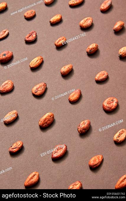 Unpeeled cocoa bean pattern on a brown background. Flat lay. Diagonal layout can be used for your creativity