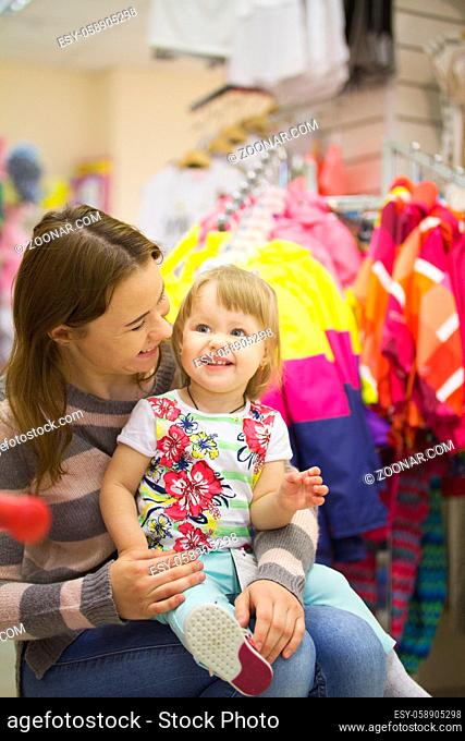 Happy woman with little daughter at garment supermarket, telephoto shot