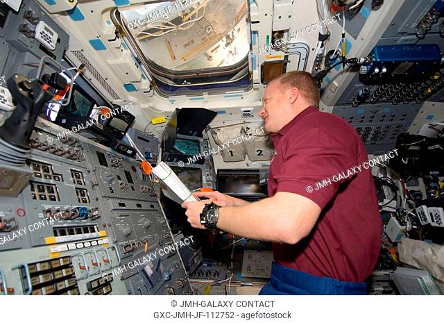 Astronaut Eric Boe, STS-126 pilot, looks over a procedures manual on the aft flight deck of the Space Shuttle Endeavour, scheduled to undock from the...