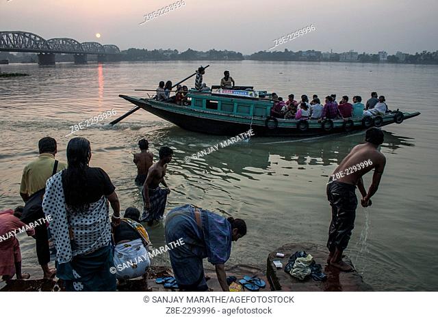Devotees at the Hindu Dakshineshwar temple (Kali temple) pay obeisance to river Ganges as a boat ferries people, in Kolkata (Calcutta), West Bengal, India