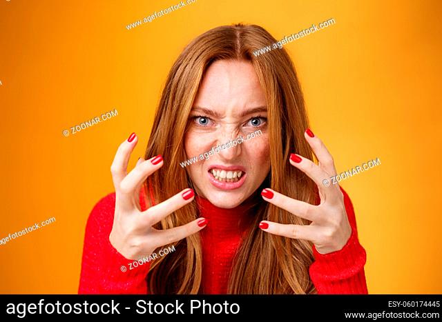 Close-up sot of pissed and angry redhead woman raising hands and clenching them with anger and outrage being irriated and annoyed grimacing from dislike