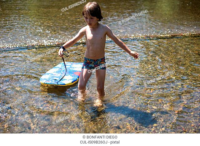 Boy ankle deep in water with body board