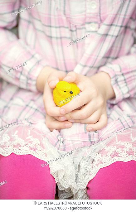 Hands of little girl holding plastic yellow bird