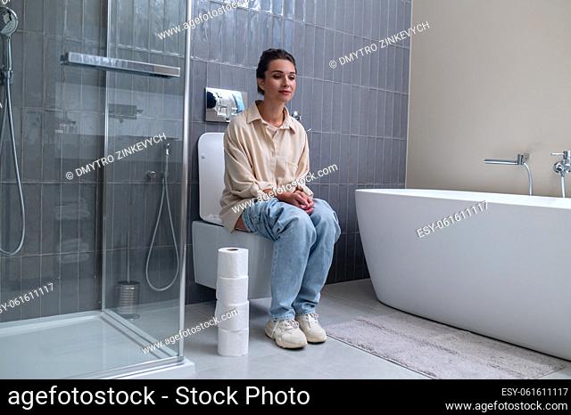 In the toilet. A young woman sitting on a toilet bowl