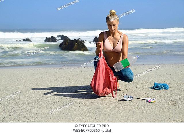 Pregnant woman cleaning the beach from plastic waste