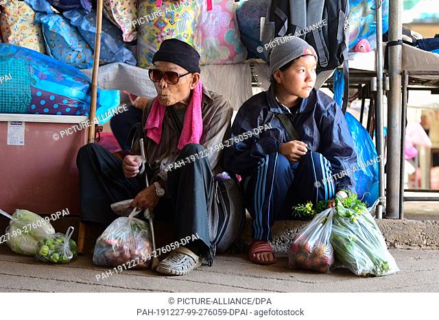 21 October 2019, Thailand, Samoeng Tai: An older man and a boy are sitting in a market next to their shopping. Photo: Sebastian Kahnert/dpa-Zentralbild