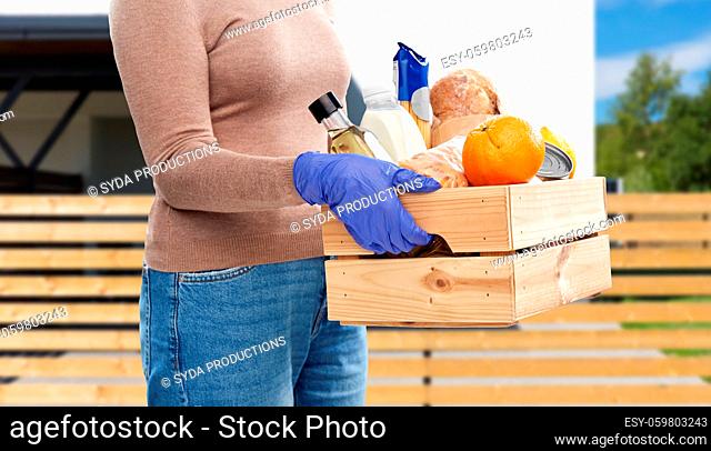 woman in gloves with food in wooden box
