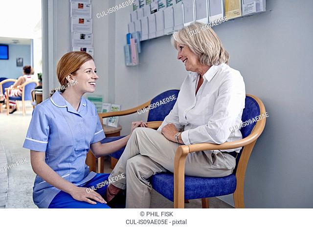 Female patient with nurse in hospital waiting room