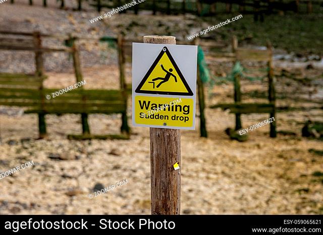 Sign: Warning sudden drop, seen in Cuckmere Haven near Seaford, East Sussex, UK