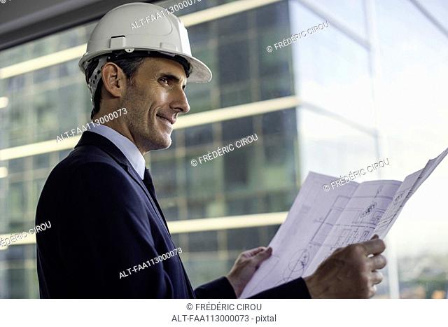 Man wearing hard hat reviewing blueprint