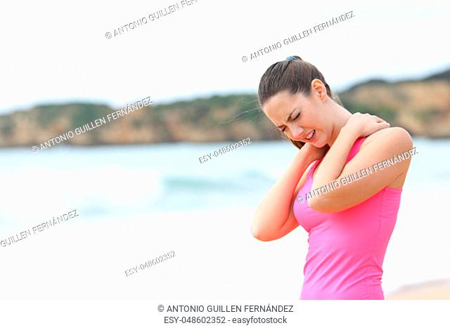 Sportswoman suffering neck ache standing on the beach