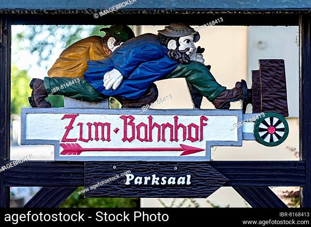 Carved wooden signpost, two men hurrying to the station, Bad Salzhausen, Nidda, Wetteraukreis, Hesse, Germany, Europe