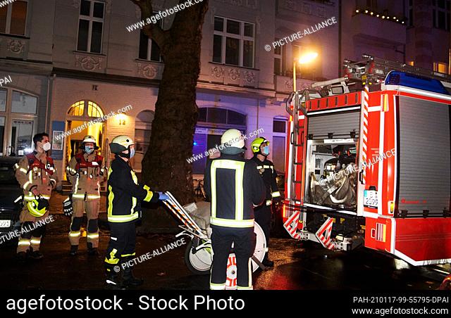 17 January 2021, Berlin: Five firefighters stand behind an emergency vehicle and load. In the Muthesiusstraße in Steglitz a fire broke out in the 1st floor...