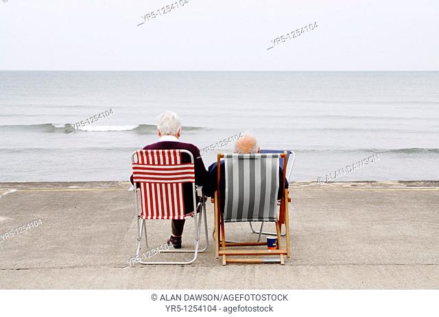 Elderly couple on deckchairs at the coast  Whitby, North Yorkshire, England