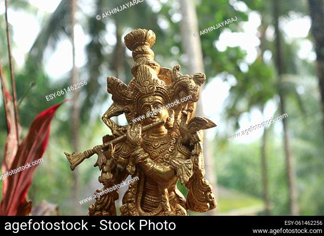 A close up shot of lord krishna brass idol in golden color