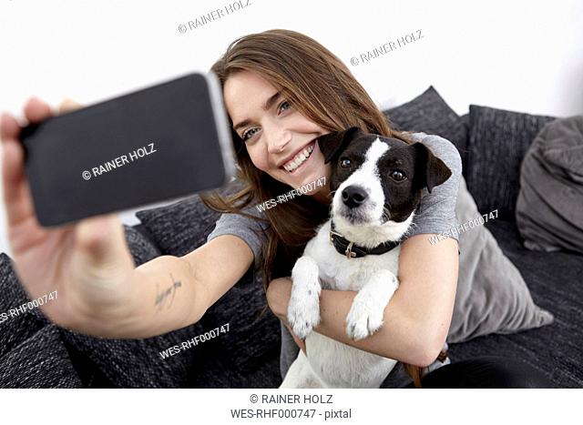 Young woman taking selfie with dog