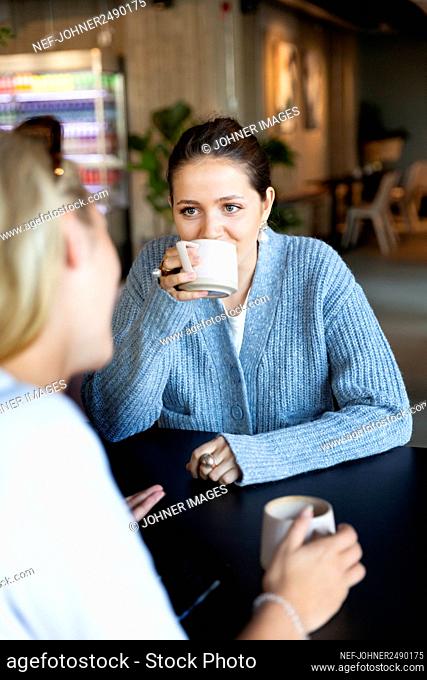 Smiling female friends talking in cafe