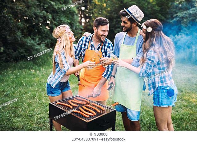 Cheerful friends spending time in nature and having barbecue