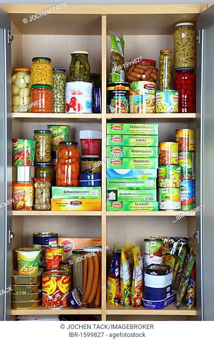 Cupboard filled with various packaged foods in glass jars and tin cans