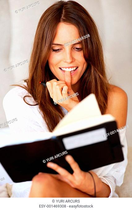 Portrait of a beautiful young female reading a diary