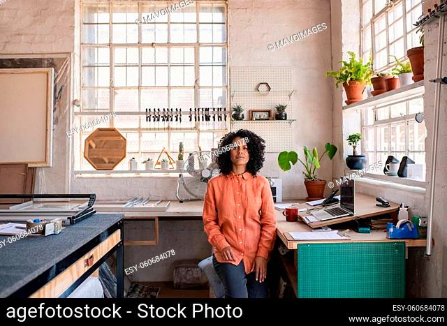 Portrait of a confident young woman sitting at a desk and working on a laptop in her picture framing studio