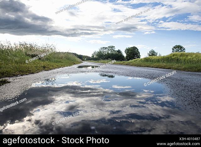 Reflection of the sky in a puddle of water after the rain on a country road, Eure-et-Loir department, Centre-Val-de-Loire region, France, Europe