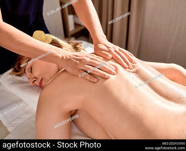 Mature woman giving back massage to senior female at health spa