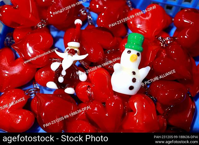 05 December 2023, Saxony-Anhalt, Derenburg: Glass figures such as a snowman and Santa Claus lie in a container with glass hearts