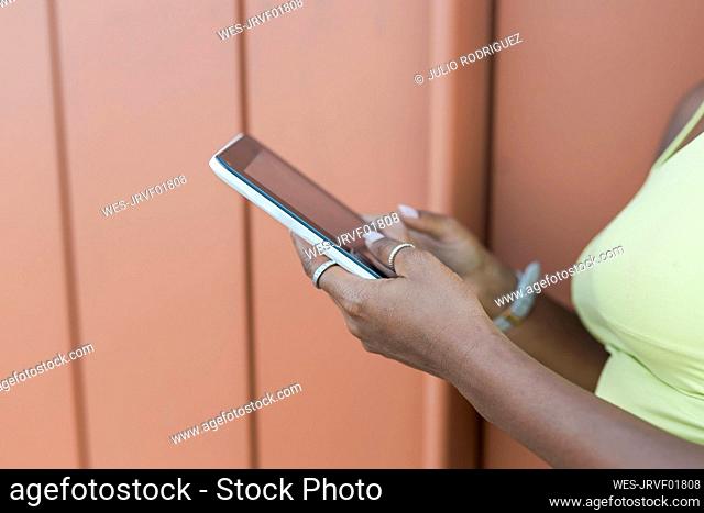 Woman using smart phone by wall
