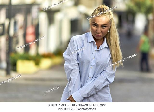 cute woman in business shirt in summer sun, walking down the public road. Russian ethnicity. In holiday destination Hersonissos, Crete, Greece