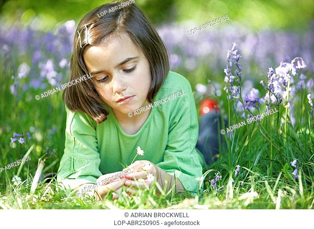 England, Buckinghamshire, Stokenchurch, A young girl lying in a wood full of Bluebells