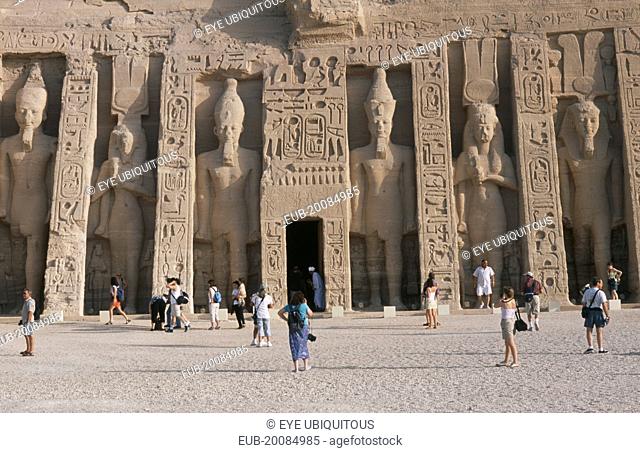 Hathor Temple . Built for Ramses II's wife Nefertari. Six standing statues caved into facade. Visitors walking in the grounds