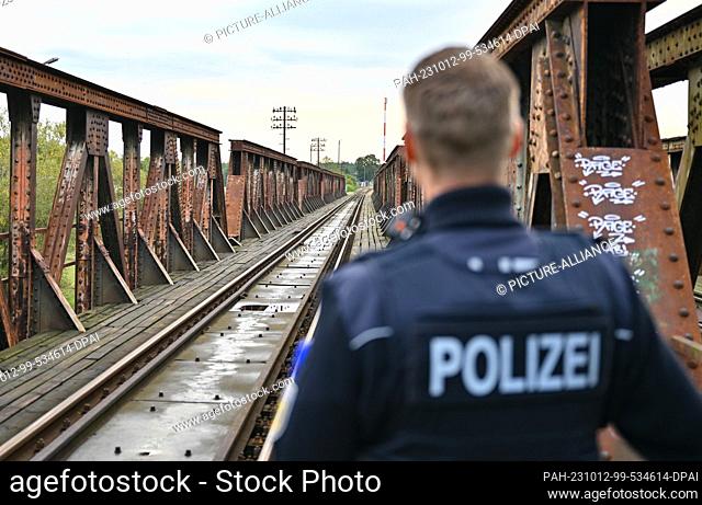 11 October 2023, Brandenburg, Forst: A federal police officer stands at a railroad bridge over the Neisse River, the German-Polish border in Forst (Lausitz)