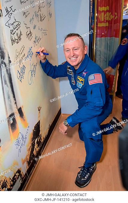 At the Korolev Museum in the Baikonur Cosmodrome in Kazakhstan, Expedition 41 Flight Engineer Barry Wilmore of NASA signs a wall mural bearing a picture of a...