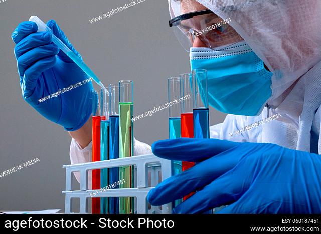 Caucasian male doctor wearing ppe suit holding test-tubes