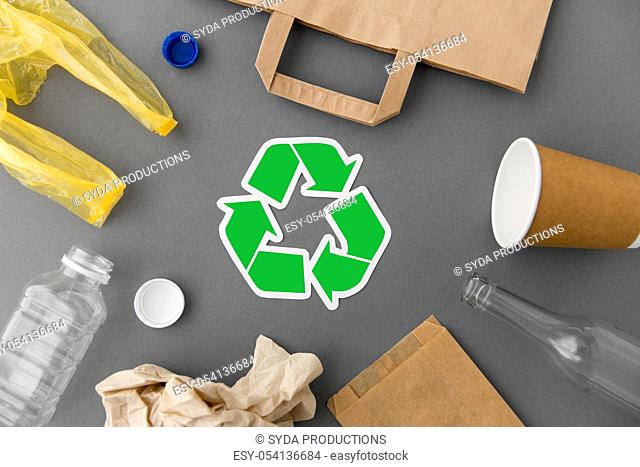 green recycle symbol with household waste on grey