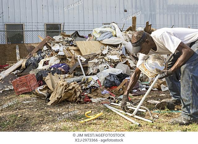 Humble, Texas - A man looks for metal and other things that can be salvaged in piles of debris from the Mana Family Worship Center