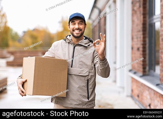 smiling delivery man with parcel box showing ok