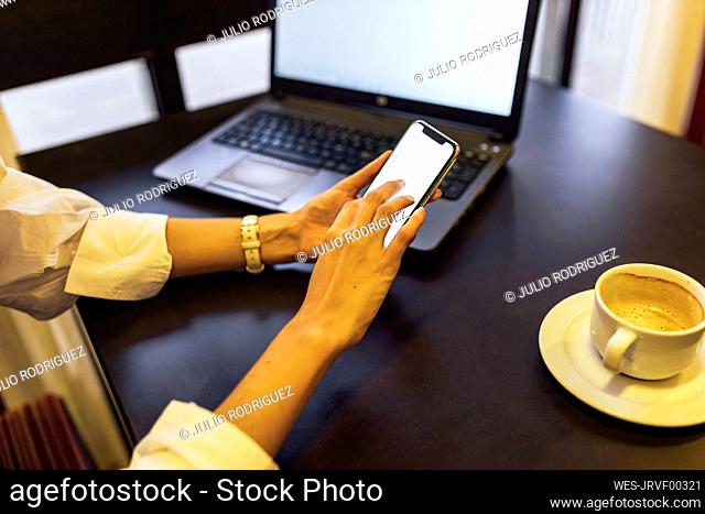 Woman using mobile phone sitting at cafe
