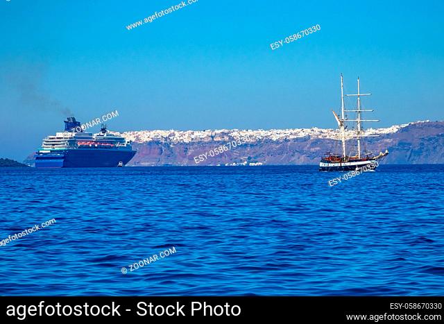 Greece. Sunny day off the coast of Santorini. Old three-masted ship and multi-deck cruise ship