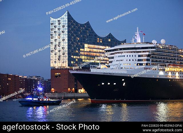 19 August 2022, Hamburg: The Queen Mary 2 cruise ship sails through the Port of Hamburg past the Elbphilharmonie Concert Hall to kick off Cruise Days in the...