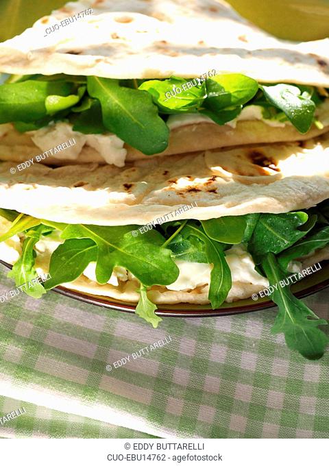 Piadina with Squacqurone cheese and rucola salad is a thin Italian flatbread, typically prepared in the Romagna region, Emilia Romagna, Italy, Europe