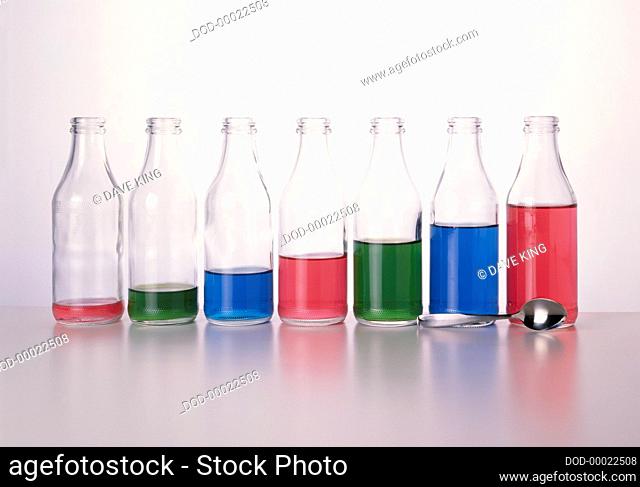 Milk bottle xylophone consisting of seven bottles of varying amounts of coloured water and a metal spoon, in a row