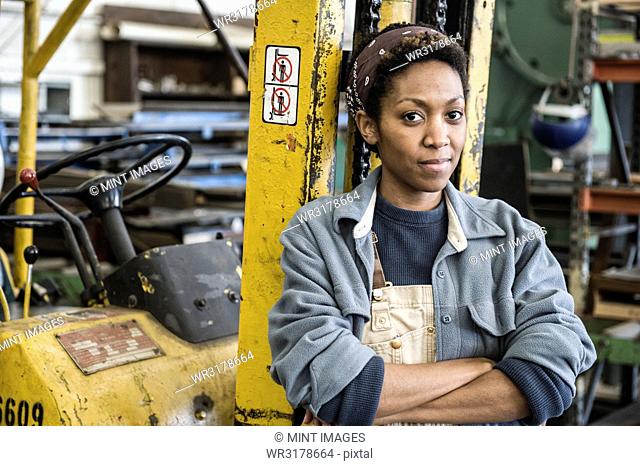 Black woman factory worker and a fork lift in a sheet metal factory