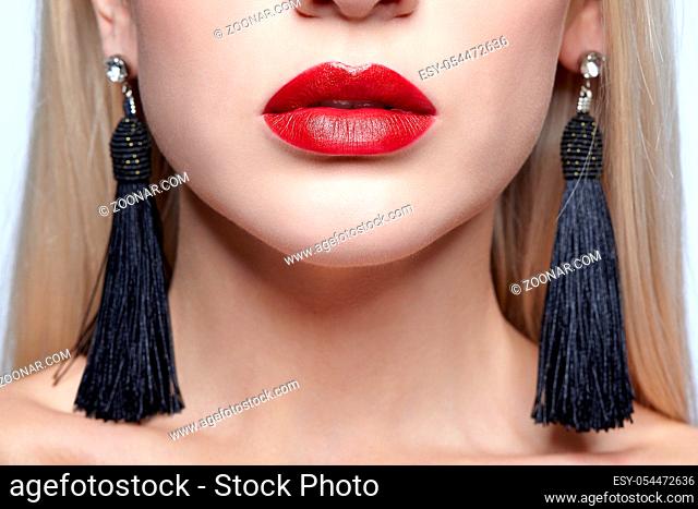 Close-up macro portrait of beauty young blonde woman face and black panicle earrings