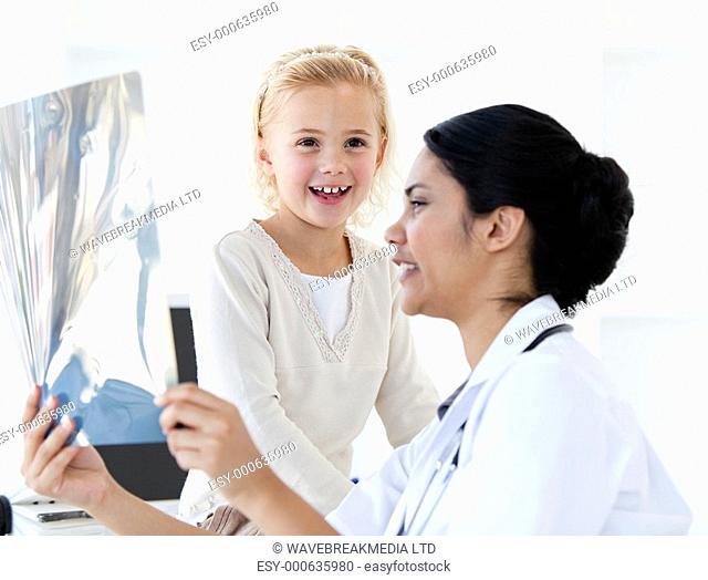 Caring female doctor showing an x-ray to a little girl in a practice