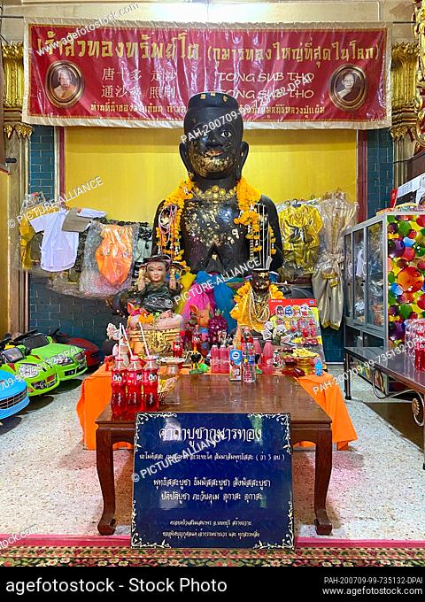 23 June 2020, Thailand, -: Lemonade stands as an offering in the temple Wat Samngam in front of a Kuman Thong figure, which is supposed to contain ashes with...
