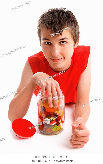 A boy places his hand into a lolly jar filled with a variety assortment of soft sweet confectionery