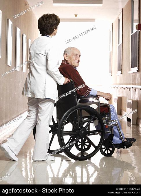 Nurse wheeling elderly man in wheelchair away